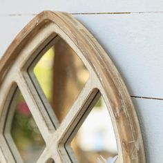 a wooden window frame hanging on the side of a white wall with a bird in it