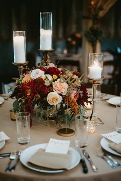 the table is set with candles, plates and napkins for an elegant centerpiece