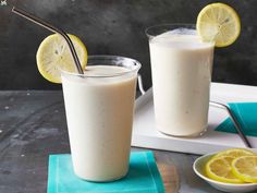 two glasses filled with lemonade sitting on top of a table