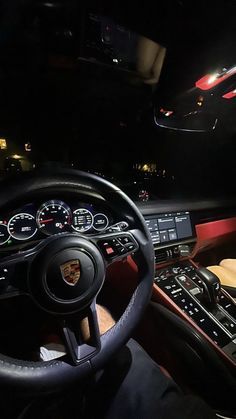 the interior of a car with steering wheel, dashboard and dash lights lit up at night