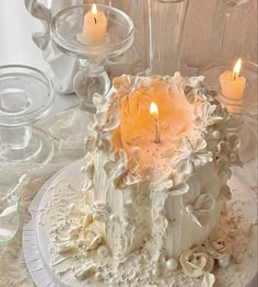 a white cake sitting on top of a table covered in frosting and lit candles