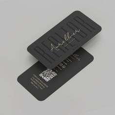 two black business cards with gold foil lettering on the front and back of each card