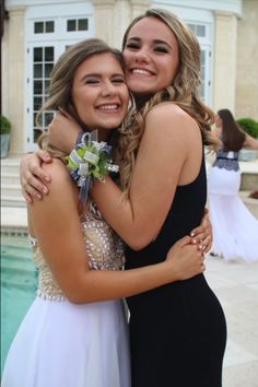 two young women hugging each other in front of a swimming pool at a wedding reception