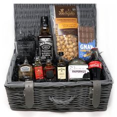 a wicker basket filled with liquor, nuts and condiments on a white background