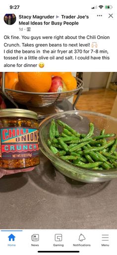 some green beans and oranges are on the counter next to a jar of chili