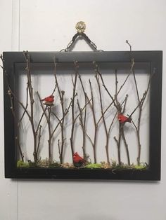 two red birds perched on branches in a shadow box with moss and gold leaf accents