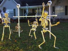 three skeletons playing with a soccer ball in front of a house decorated for halloween time