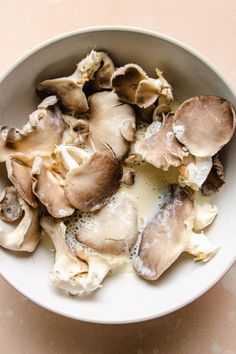 a white bowl filled with mushrooms on top of a table