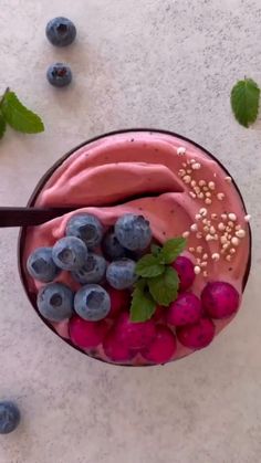 a smoothie topped with blueberries, raspberries and mint sprinkles