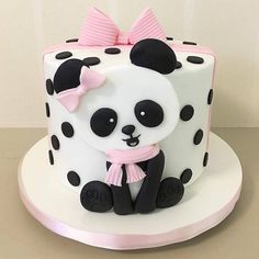 a panda bear cake with black and white polka dots on the top, pink ribbon around its neck