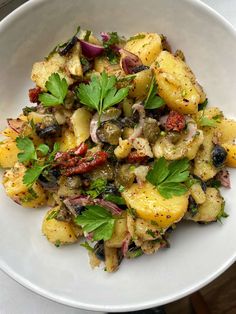 a white bowl filled with potatoes and herbs