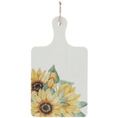 a white cutting board with sunflowers painted on the front and back of it