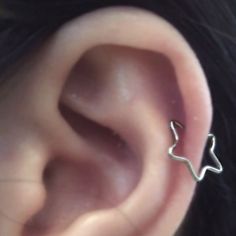 an ear is shown with a small silver nose piece in the middle and a tiny star on