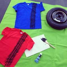 an assortment of clothes and tools laid out on a green sheet with a tire in the background