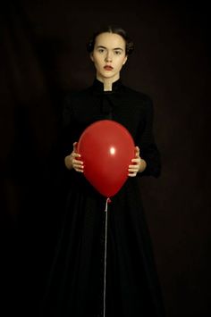 a woman holding a red balloon in front of her face