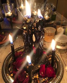 three candles are lit in a bowl with flowers