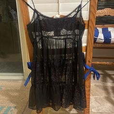 a black dress hanging on a rack in front of a door with a blue ribbon