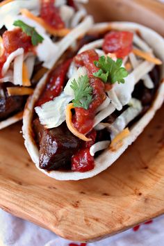 two tacos with toppings on a wooden plate