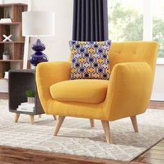 a yellow chair sitting on top of a wooden floor next to a lamp and window