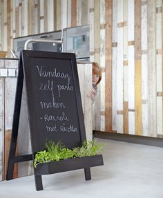 a chalkboard sign with plants in it next to a kitchen counter and wallpaper