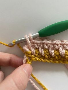 someone is crocheting the stitchs together to make a piece of knitting material