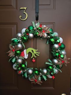 a christmas wreath on the front door with ornaments hanging from it's side and number 5