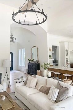 a living room filled with furniture and a large chandelier above the couches