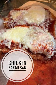 two chicken parmesan sandwiches with sauce and cheese on top, sitting in a glass container