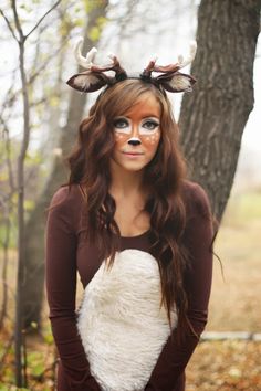 a woman with deer antlers on her head wearing a white heart shaped costume in the woods