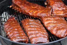 ribs are being cooked on the grill with sauce