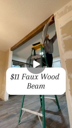 a man on a ladder painting the wall in his house with text overlay that reads $ 11 faux wood beam