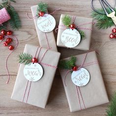 four wrapped presents sitting on top of a wooden table next to christmas decorations and scissors