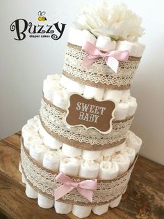 a three tiered diaper cake with pink and white flowers on top is shown