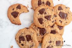 chocolate chip cookies are arranged on a white surface