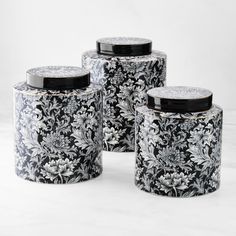 three black and white canisters with floral designs