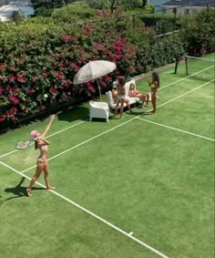 two women are playing tennis on the grass with one woman holding an umbrella over her head