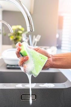 a person washing their hands under a faucet in a kitchen sink with soap