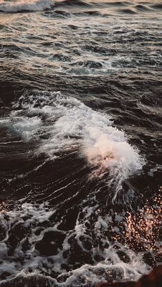 the water is choppy and foamy as it comes in from the ocean at sunset