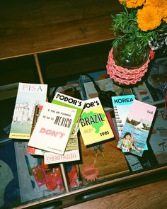 there are many books on the table with flowers in vases next to each other