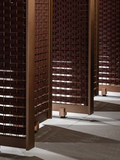 three tall wooden screens sitting next to each other on top of a cement floor in front of a window