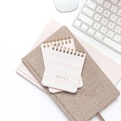 two notebooks sitting on top of each other next to a computer keyboard and mouse