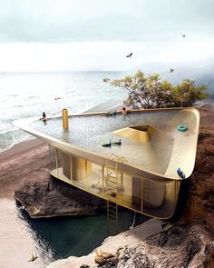 an unusual house built into the side of a cliff by the ocean with people swimming in it