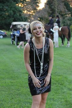 a woman in a black dress standing on the grass