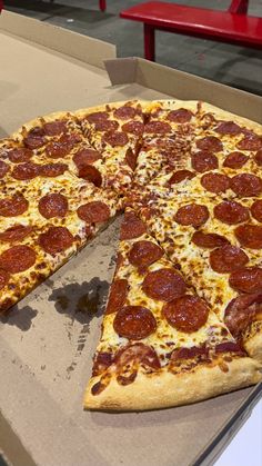 a large pepperoni pizza sitting on top of a cardboard box