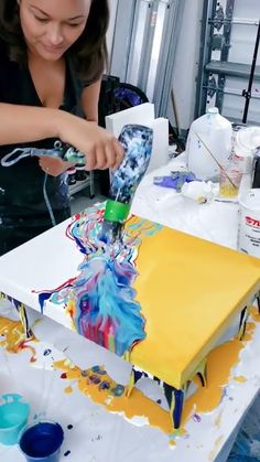 a woman is painting an art project on a table