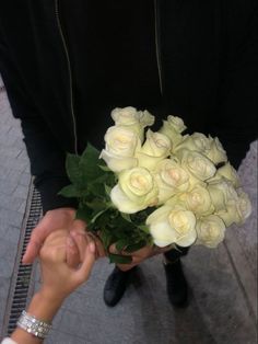 two people are holding white roses in their hands