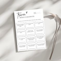 a white sheet of paper sitting on top of a table next to a flower and a plant