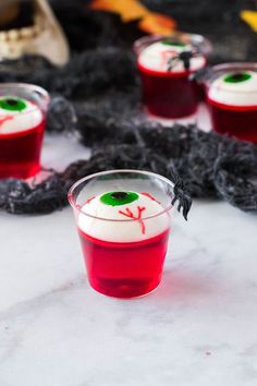 some red drinks with white and green eyes on them sitting in front of black yarn