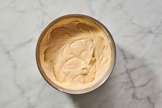 a bowl filled with cream sitting on top of a marble counter