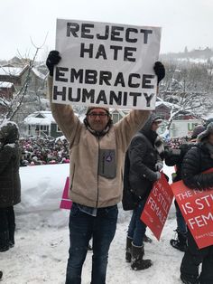 a man holding up a sign that reads respect hate embrace humanity and the state is still female